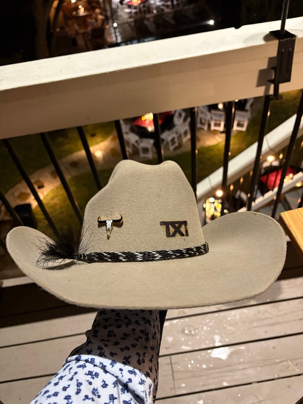Cream cowboy hat with TXi branding, a longhorn accent, feather, and braided band